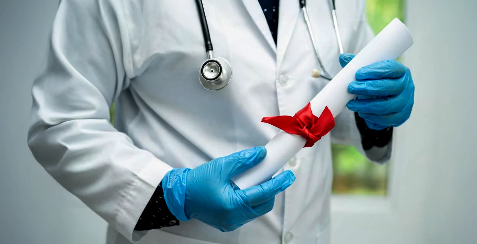 Doctor holding a rolled certificate with a red ribbon, symbolizing HITRUST certification benefits for healthcare startups