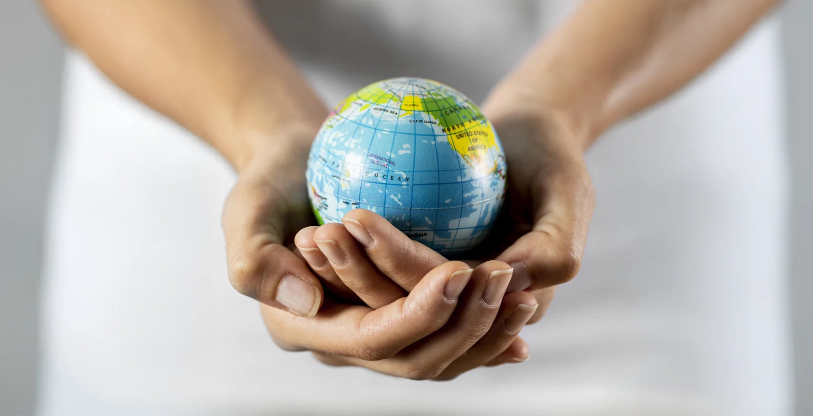 Hands holding a small globe symbolizing global adoption of HITRUST CSF as a trusted compliance and security framework.