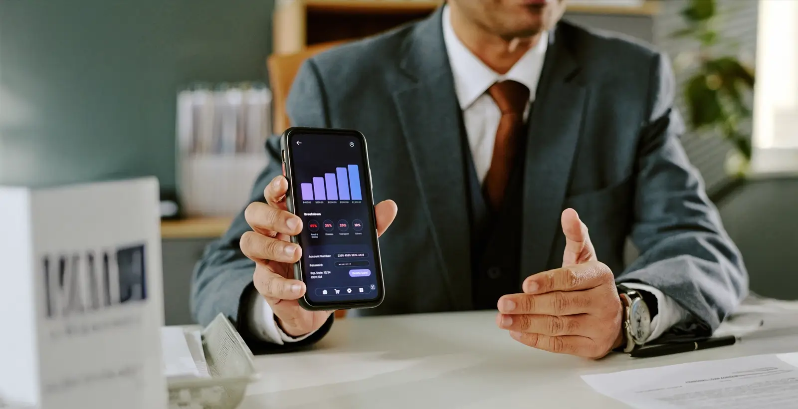 Businessman holding a smartphone displaying financial data, representing secure mobile application testing for FinTech user protection
