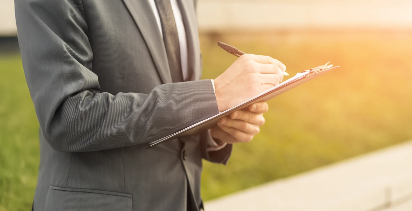 Business professional in a suit writing on a clipboard, representing the process of hiring a Virtual CISO