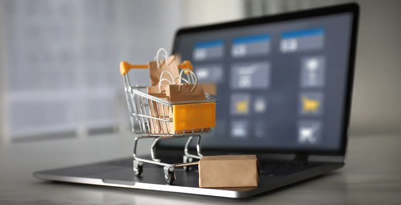 Mini shopping cart and packages on a laptop keyboard, illustrating online retail data protection and UAE PDPL requirements.
